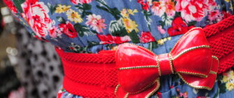 A Detail Of A Colorful Dress With A Red Bow