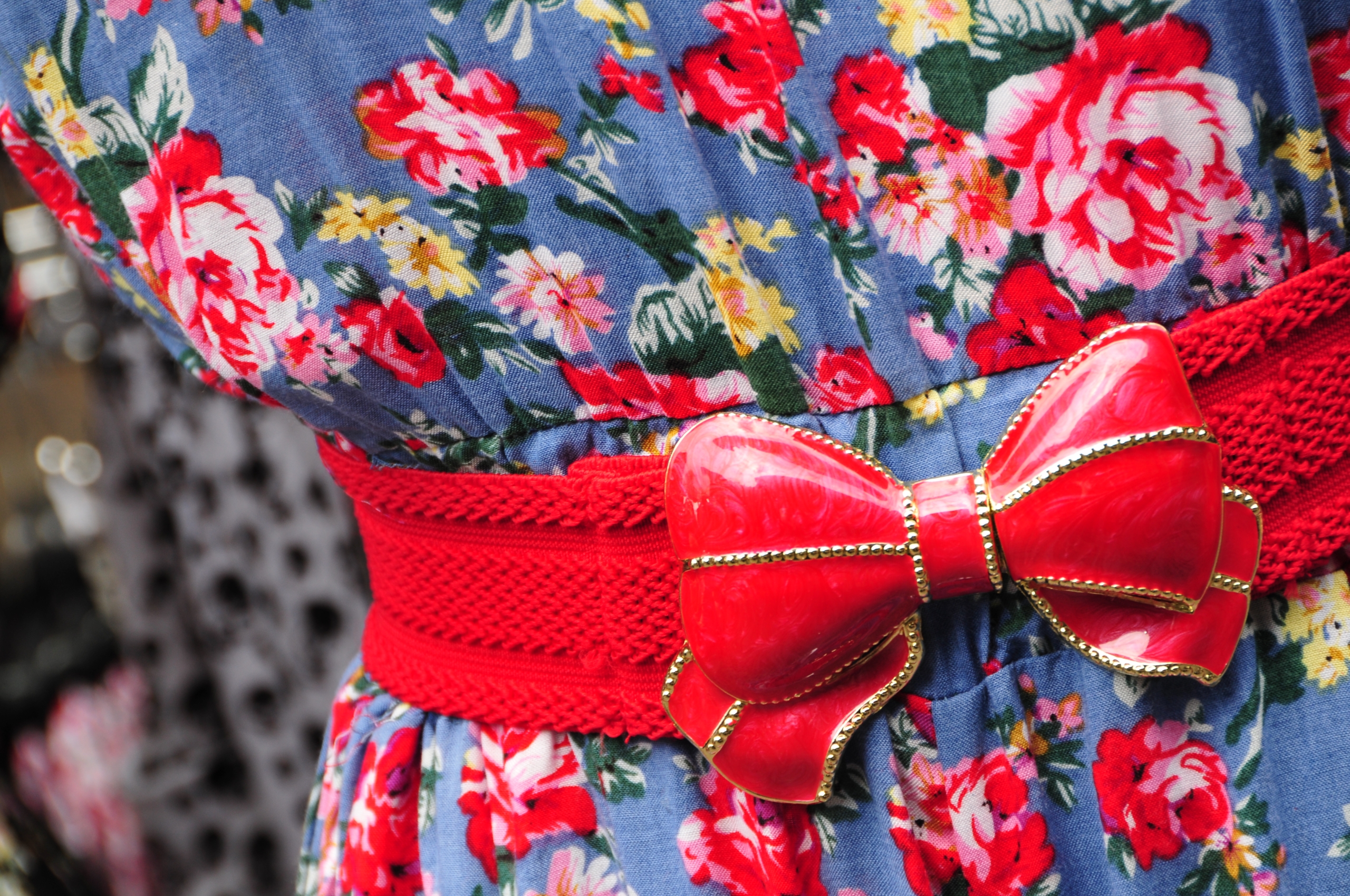 A Detail Of A Colorful Dress With A Red Bow